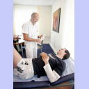 THW-Mannschaftsarzt Dr. Frank Pries erkl�rt Viktor Szilagyi, der auf einer Behandlungsliege liegt, anhand eines Modells die Verletzung im Knie.